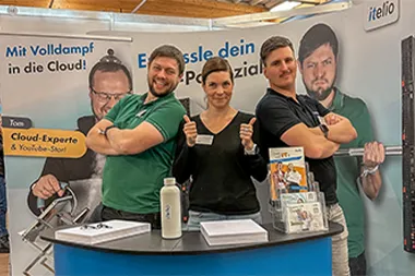 Julia Doetsch with two employees at the itelio GmbH stand at a career fair.