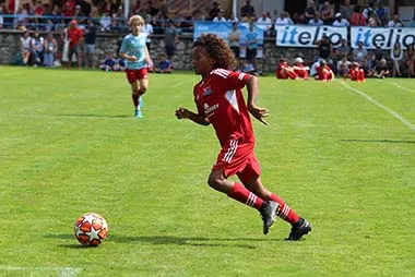 A young soccer player runs towards the ball at the itelio Cup.