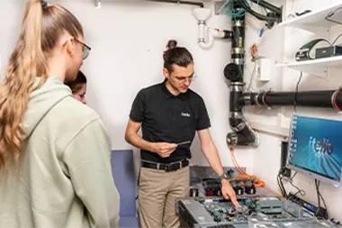 Ein Mitarbeiter von itelio erklärt zwei interessierten Mädchen das Innenleben eines Computers beim itelio Girls Day.