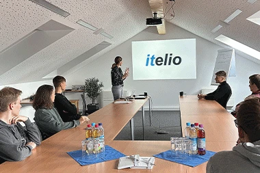 Junge Mitarbeiter von itelio bei einer gemeinsamen Besprechung mit Personalmanagerin Julia Mayr.