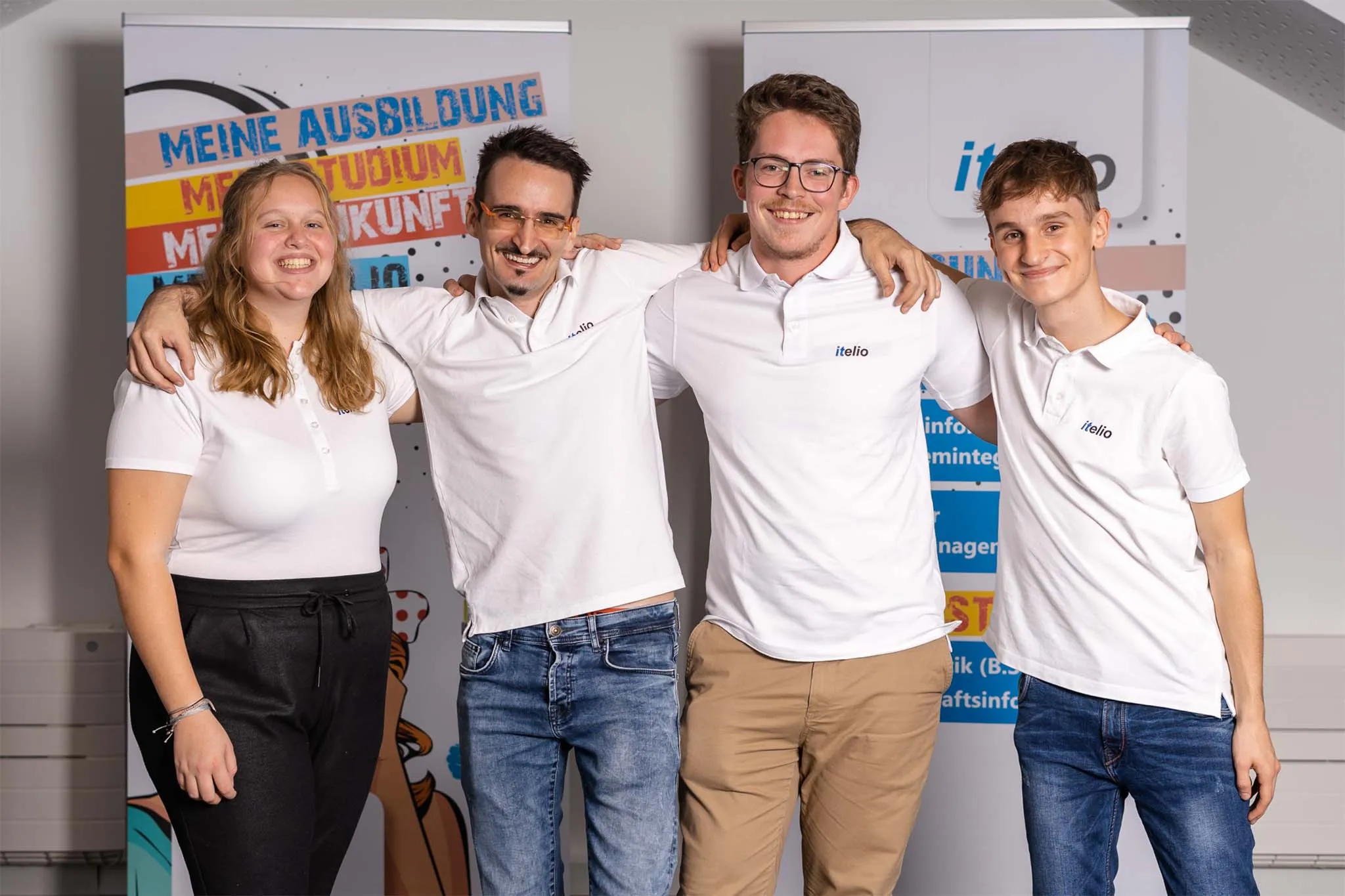 Vier Auszubildende stehen Schulter an Schulter vor einem itelio-Banner zum Thema Ausbildung, Studium, Zukunft.